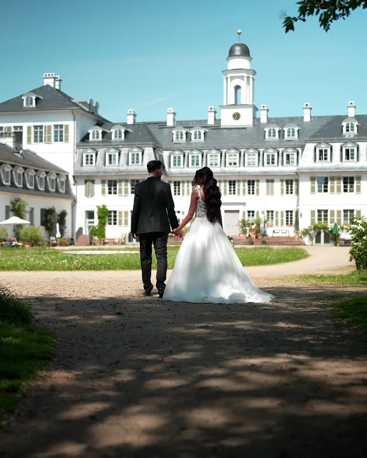 Brautpaar geht Hand in Hand auf ein Schloss zu – Elopement
